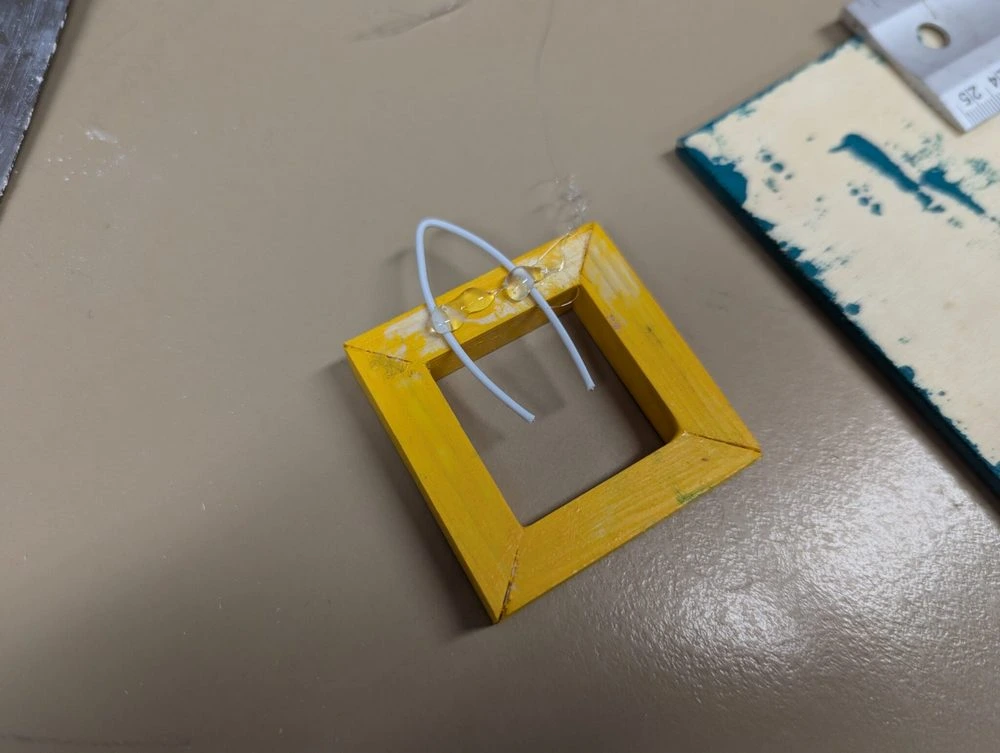 Der vier eckige Bilderrahmen erhält eine aufhänge Schnur, welche mit Heißkleber fixiert wird.