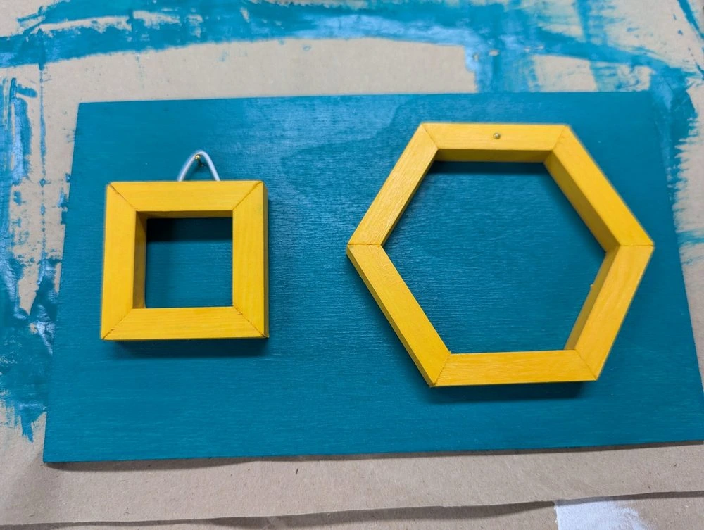 Das Hintergrundholz ist in unserem Design Grün gestrichen und die beiden Bilderrahmen in unserem Gelb