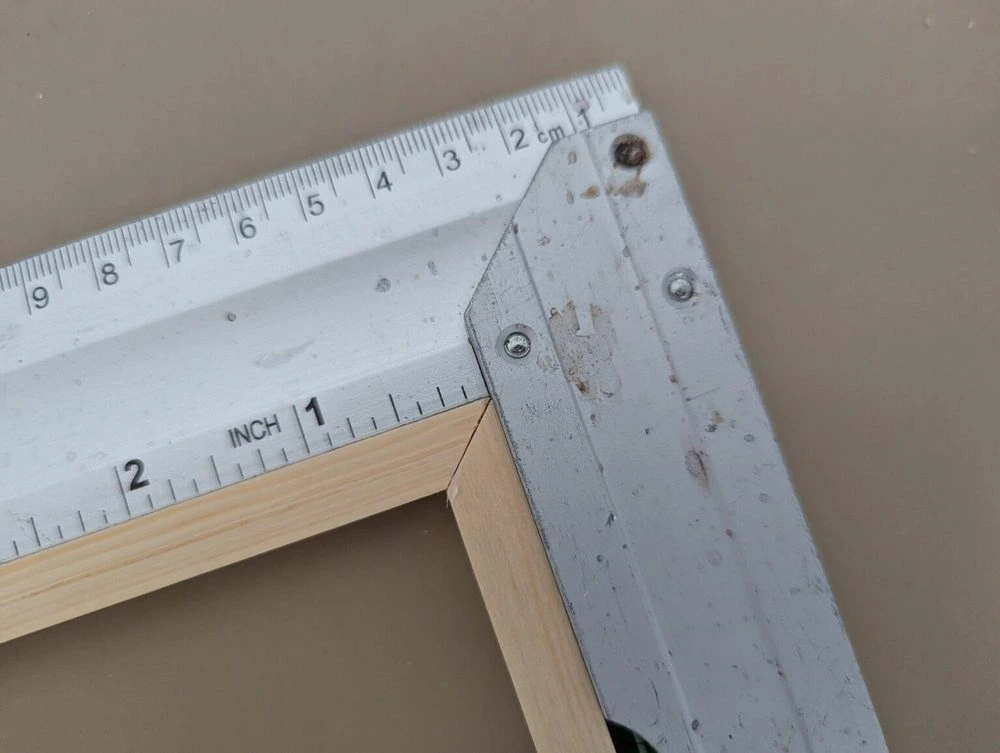 Zwei der zuvor gesägten 45^Grad winkligen Stücke liegen nun zusammen und bilden einen 90° Winkel. Um dies zu prüfen wird ein Winkel maß dran gehalten