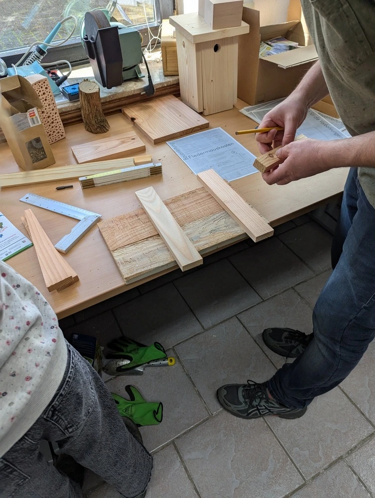 Zwei Personen bauen gemeinsam ein Vogelhaus auf.